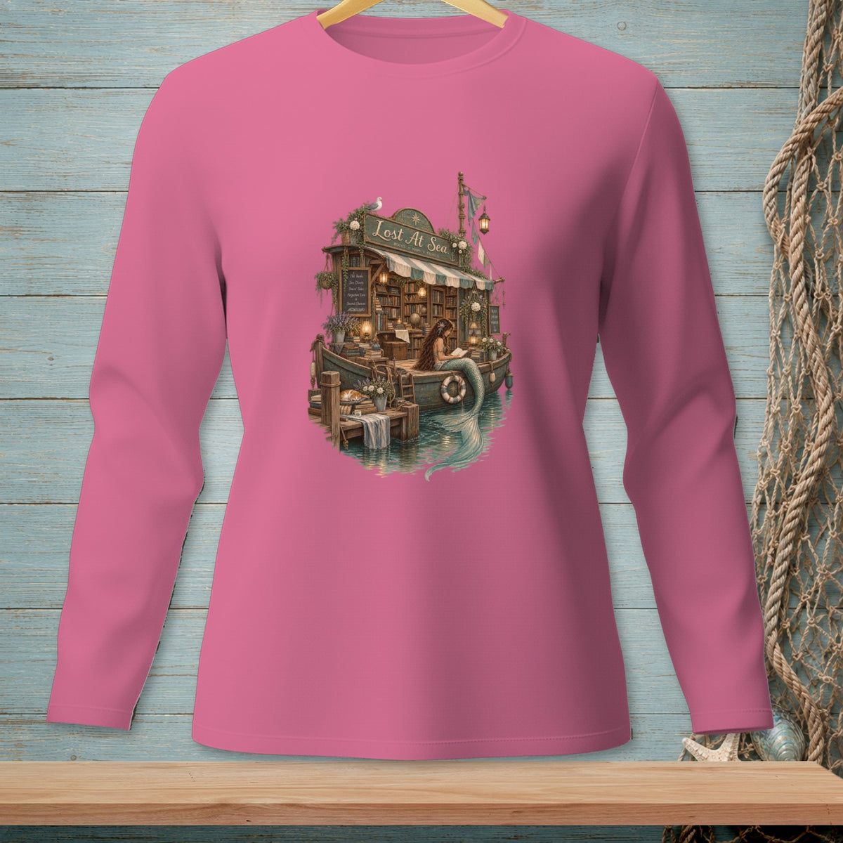 Pink long-sleeve shirt featuring a boat bookstore with a mermaid reading.