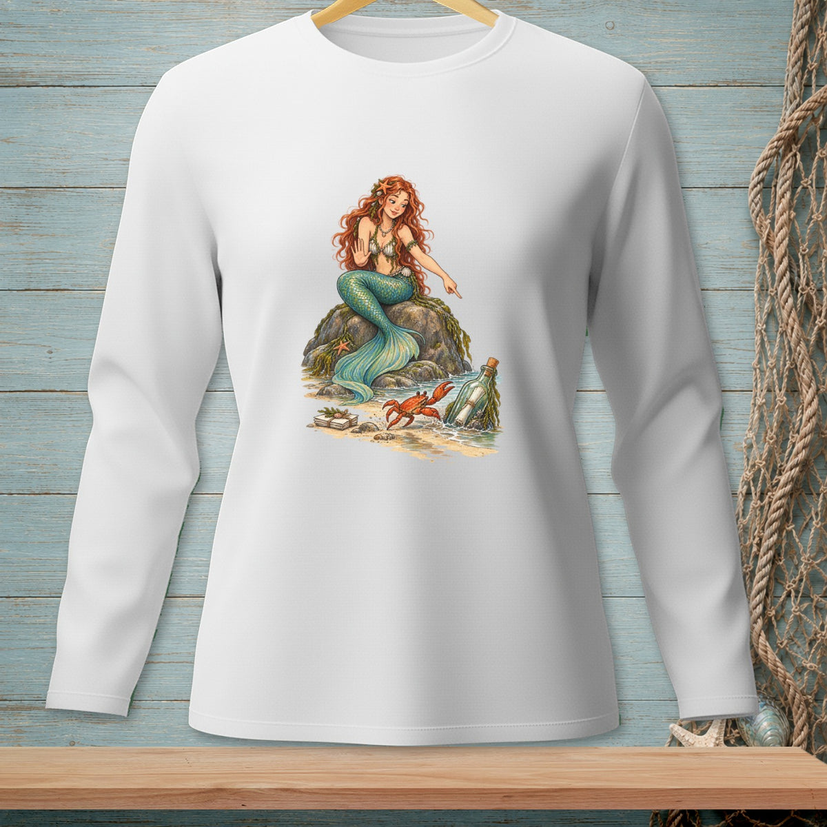 Long-sleeved white shirt with a mermaid sitting on a rock near a crab and message in a bottle.
