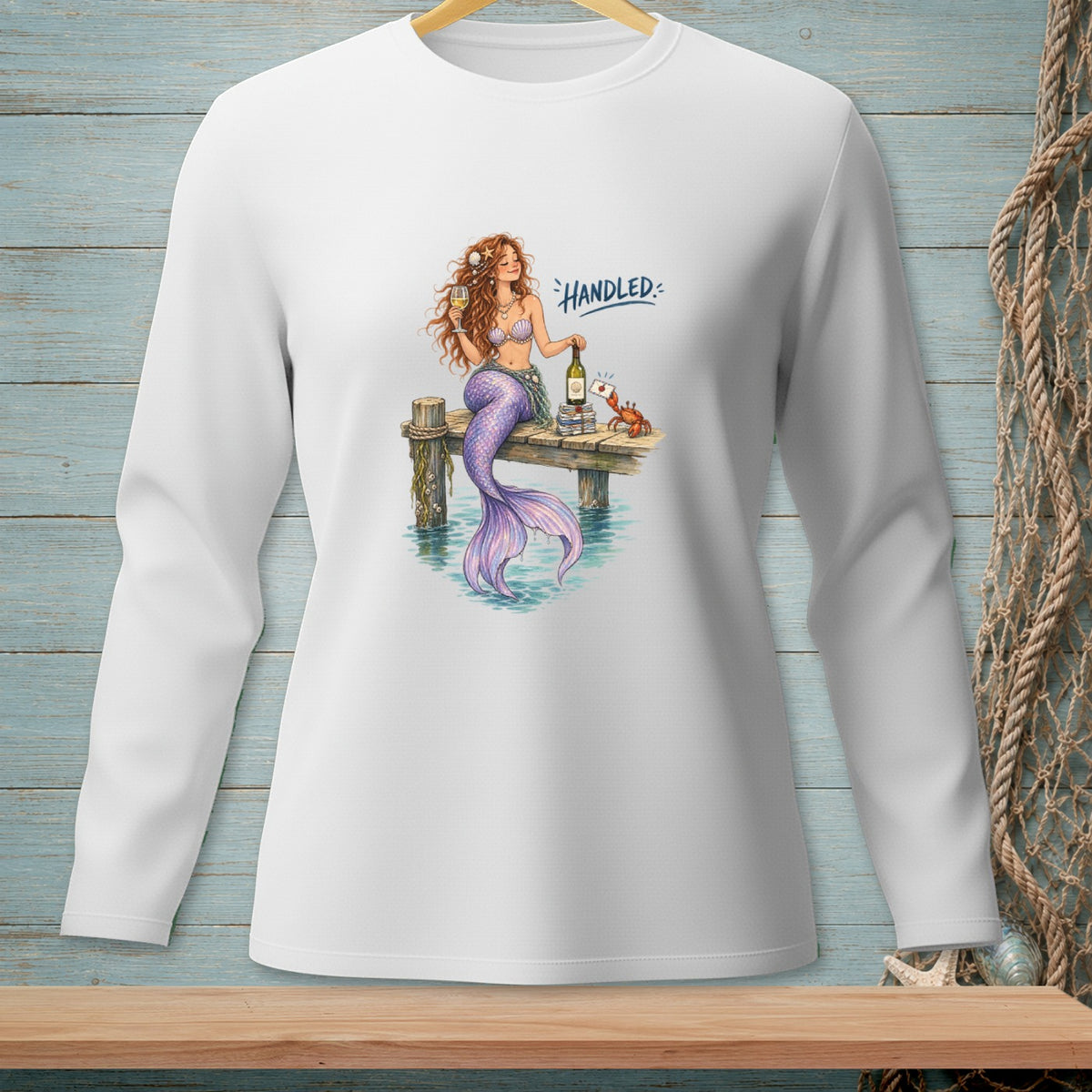 Mermaid sitting on a dock with wine and a crab, text reads "Handled".