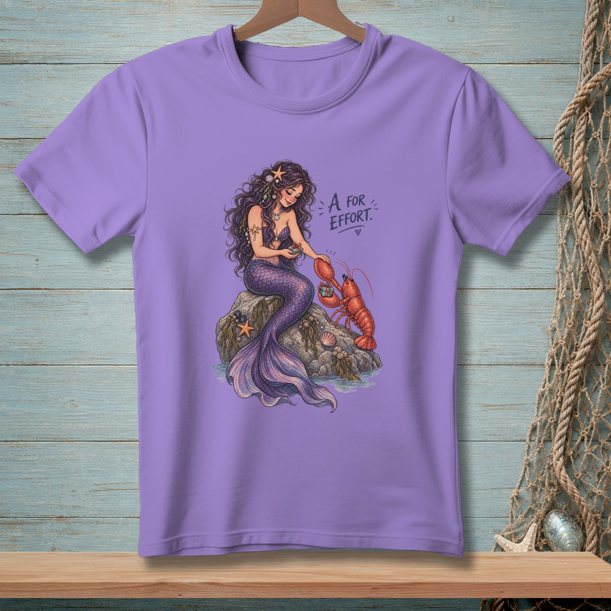 Mermaid sitting on a rock with a lobster, text "A for Effort".