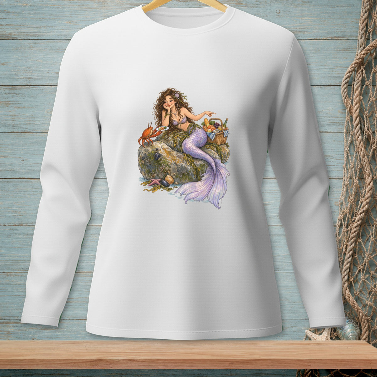 Illustration of a mermaid with a purple tail sitting on a rock with a crab and picnic basket.