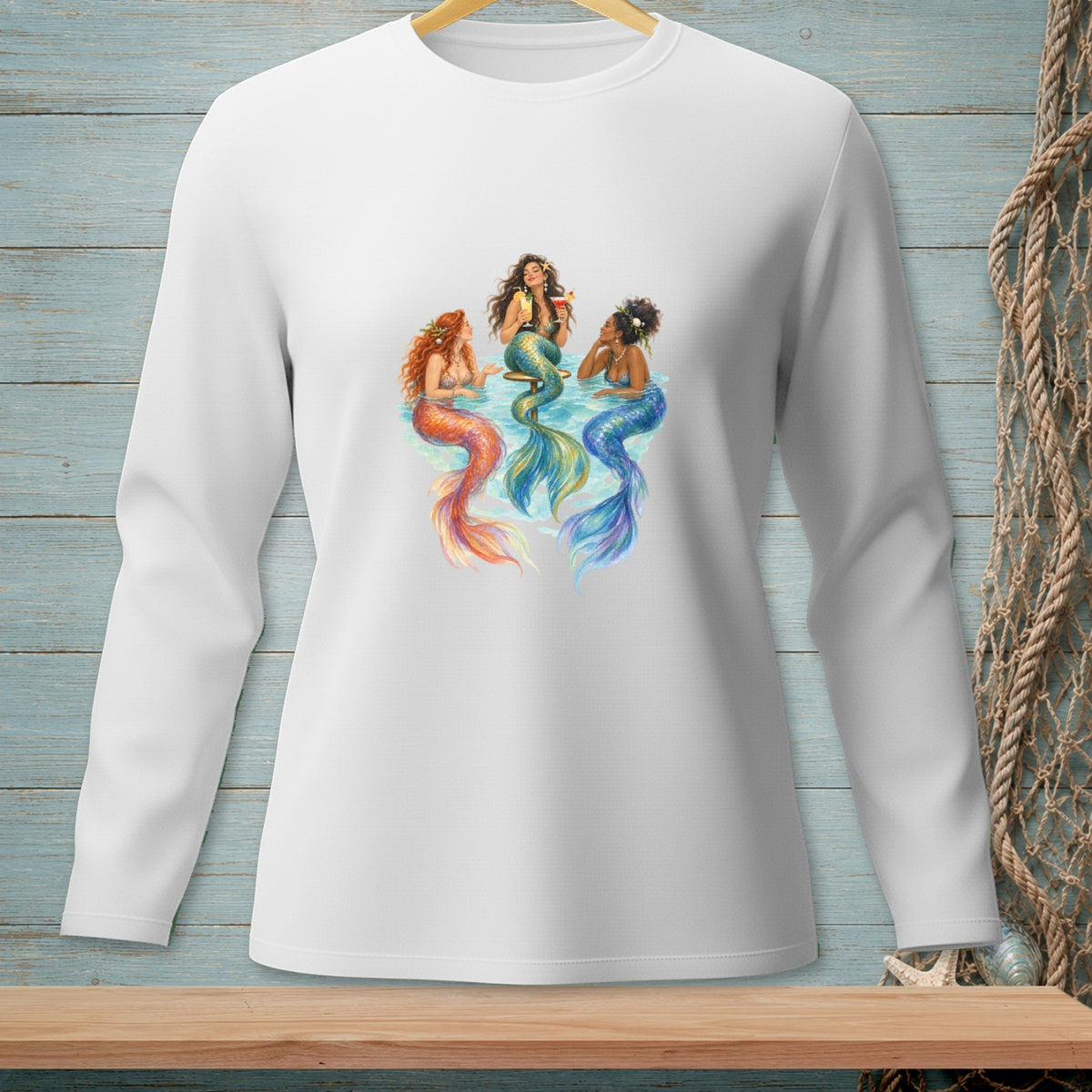 Three mermaids with colorful tails sit in water holding drinks.