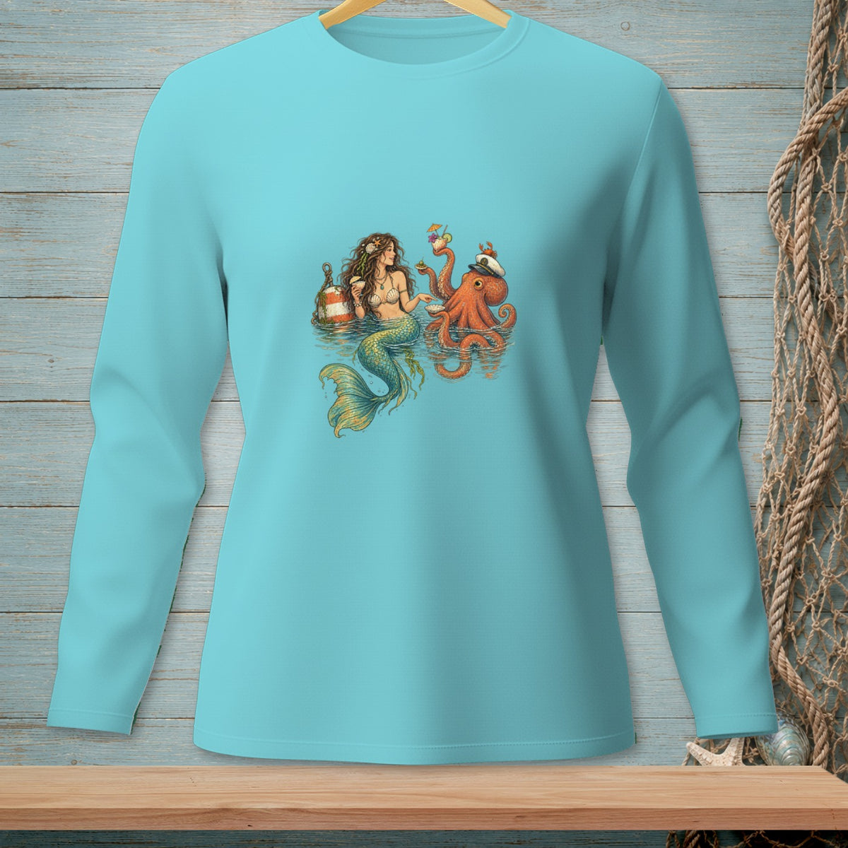 Mermaid and octopus holding drinks in water, displayed on a light blue long-sleeve shirt.