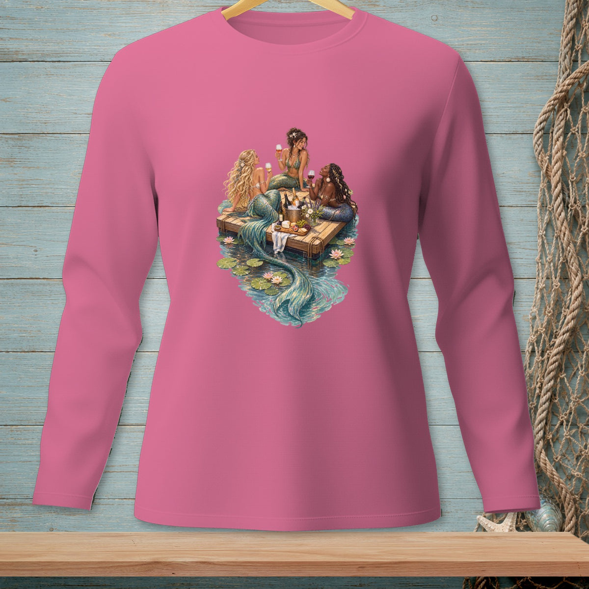Four mermaids share wine and snacks on a wooden raft in a pond.
