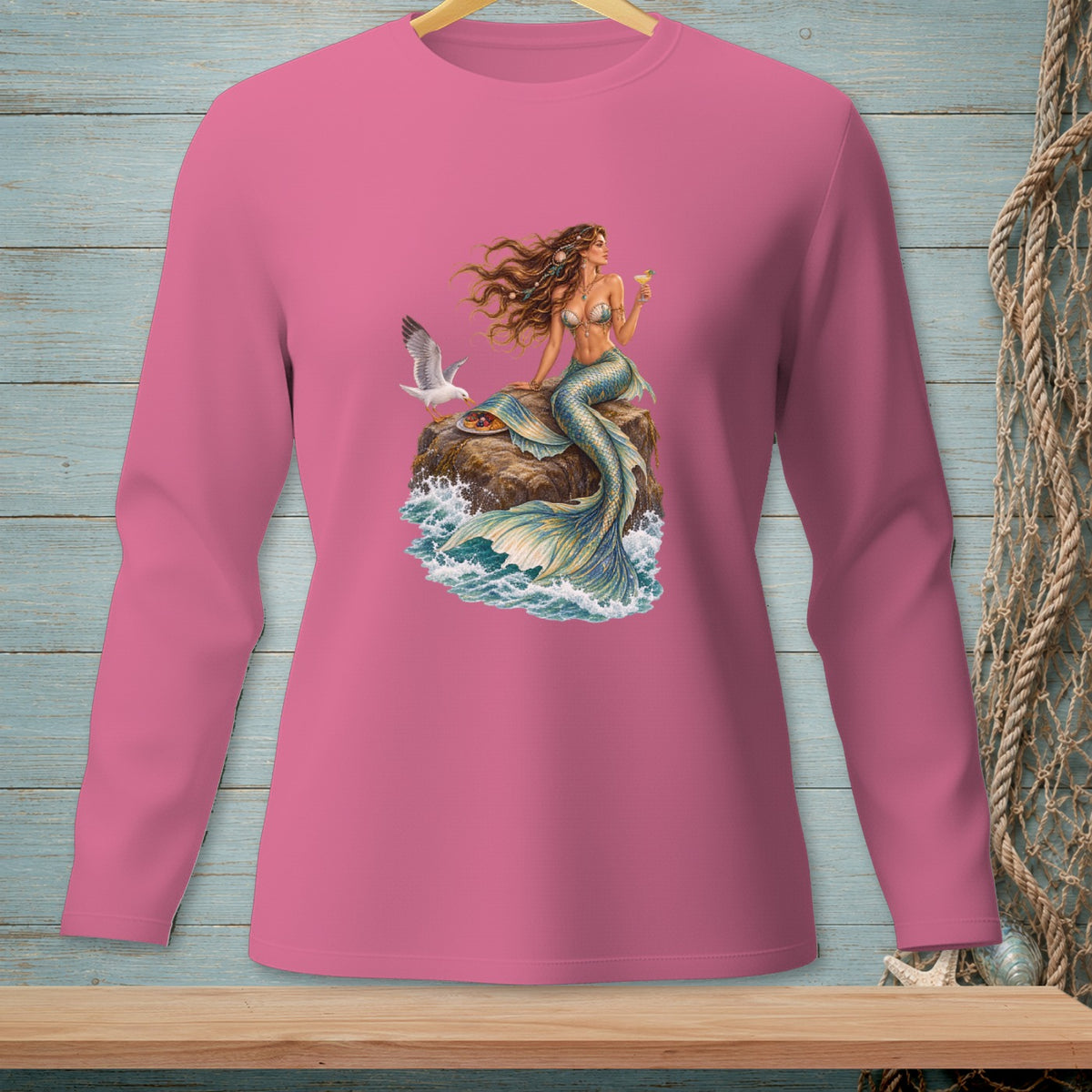Mermaid with seagull and cocktail on rock with crashing waves design on pink shirt.