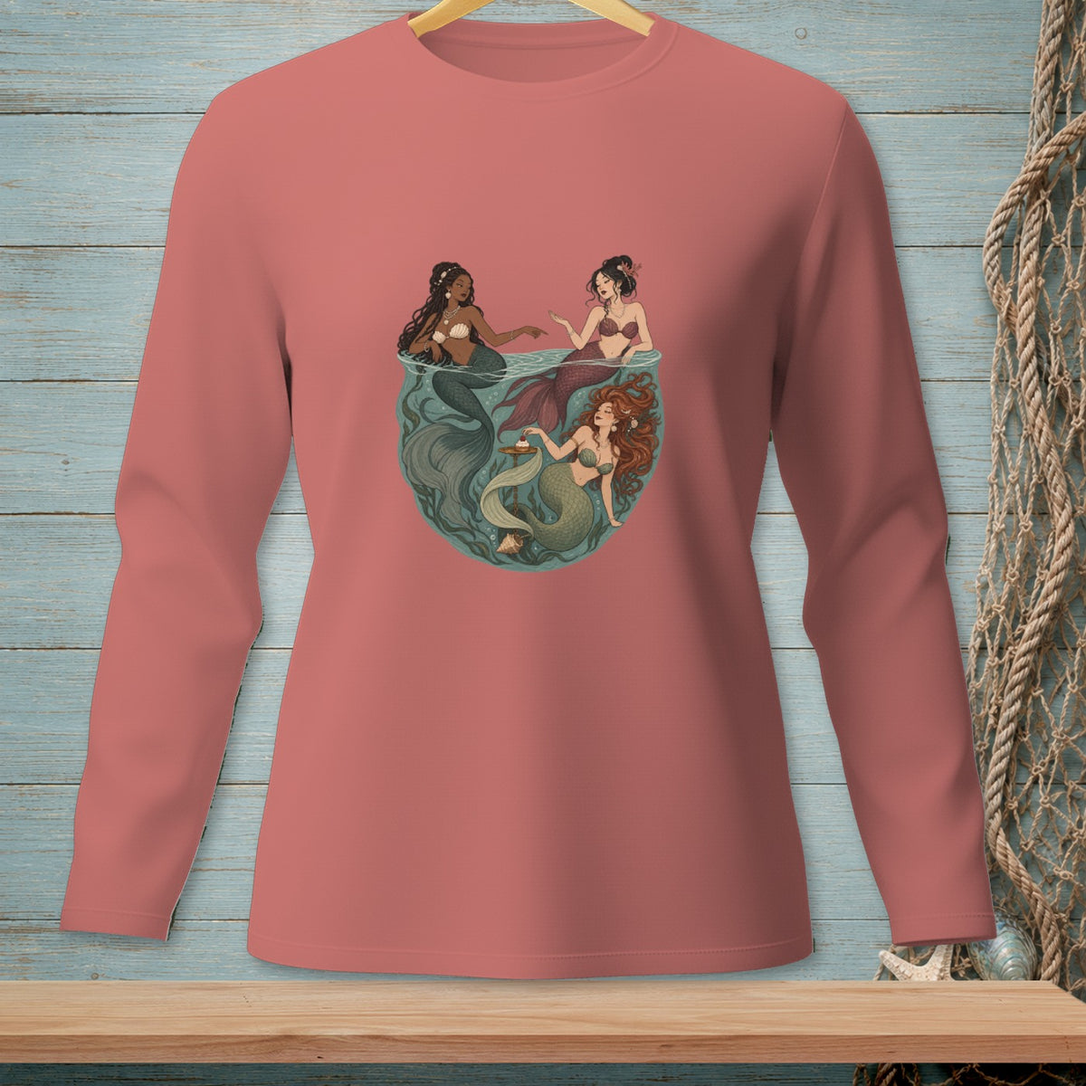 Three mermaids gathered in a circular underwater scene, one offering a seashell cupcake.