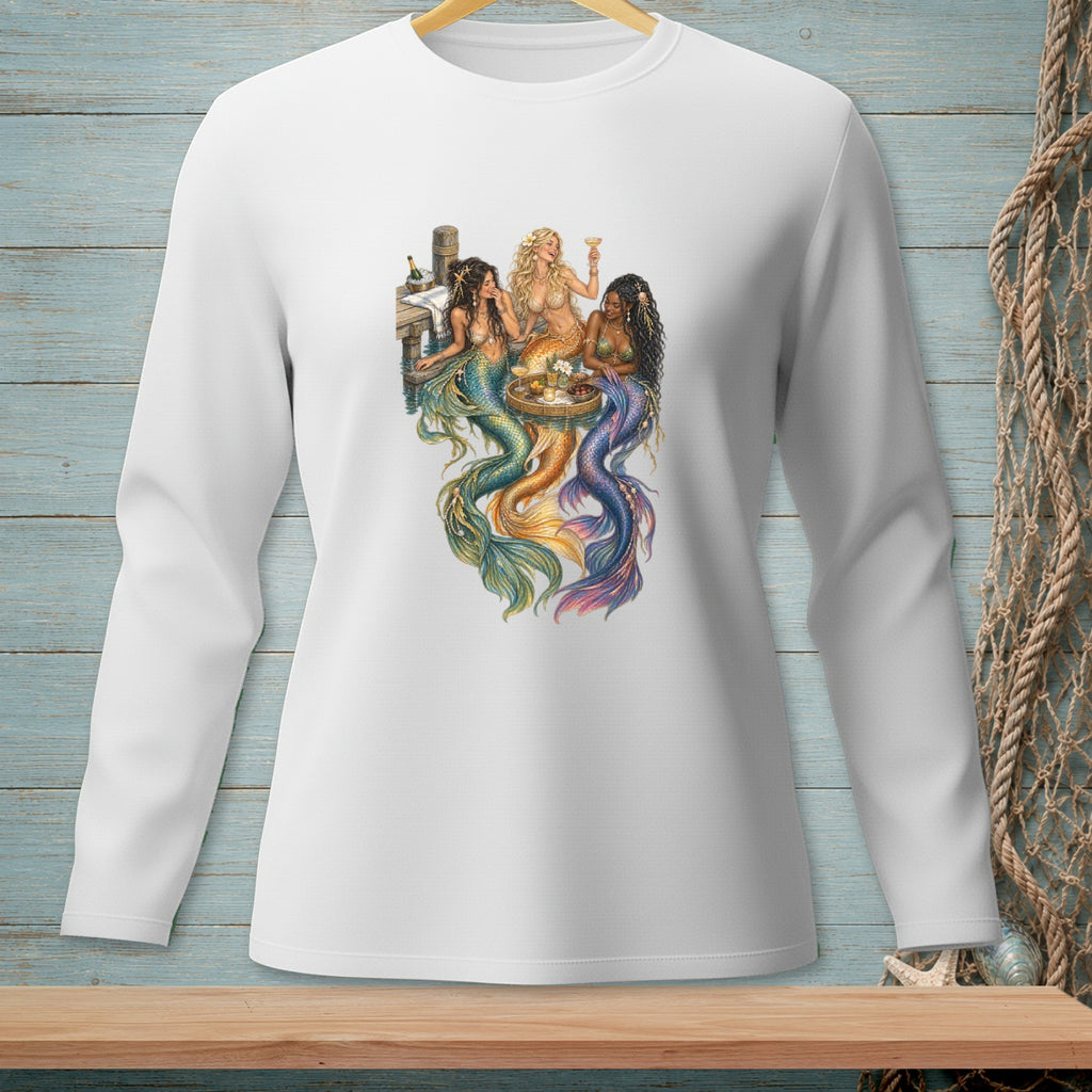 Four mermaids with colorful tails gathered around a table with drinks.