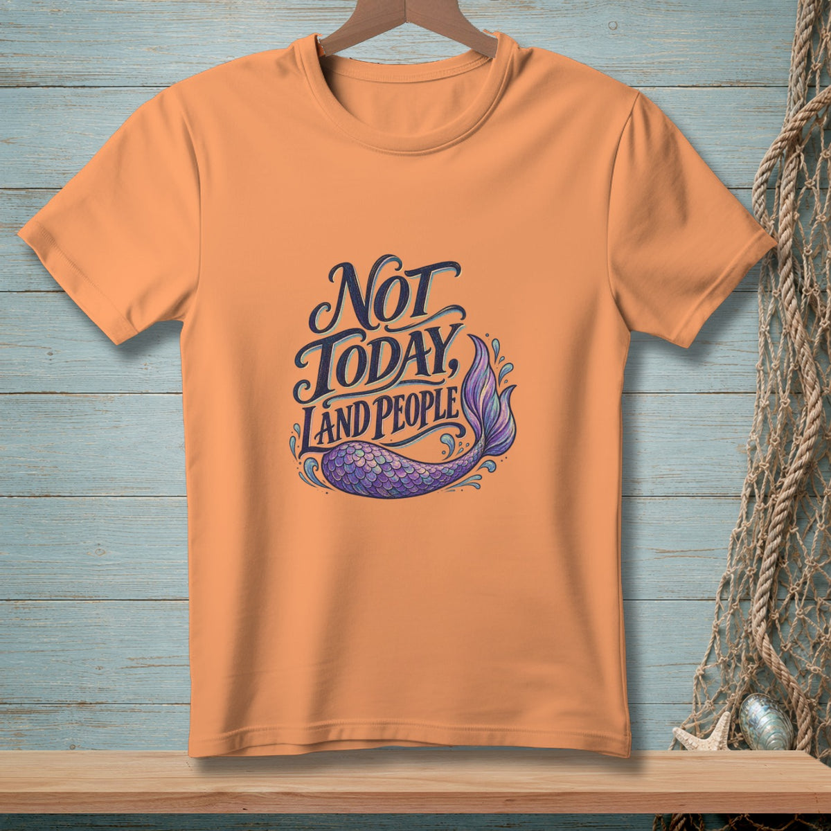 Orange t-shirt with text "Not today, land people" and mermaid tail graphic.