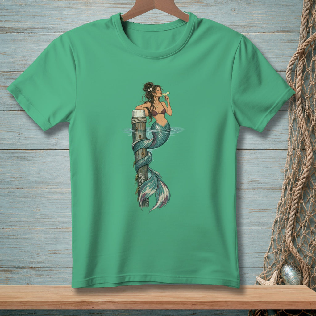 Green t-shirt featuring a mermaid wrapped around a wooden post, drinking a cocktail.