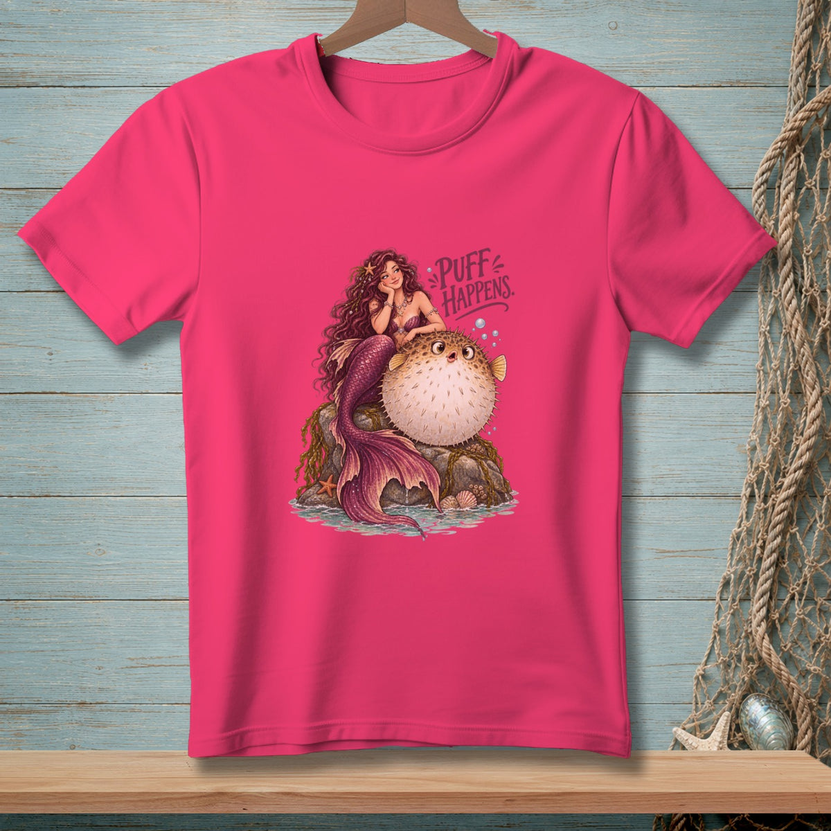 Pink t-shirt with a mermaid and pufferfish illustration saying "Puff Happens".