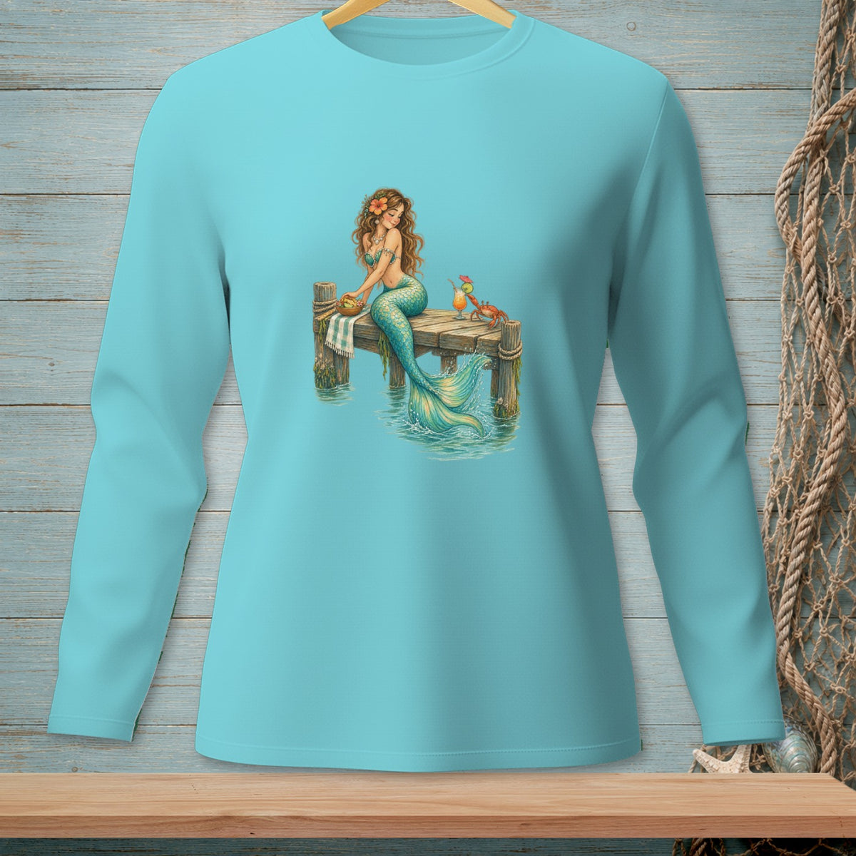 Teal long-sleeve shirt with a graphic of a mermaid sitting on a dock with drinks and a crab.