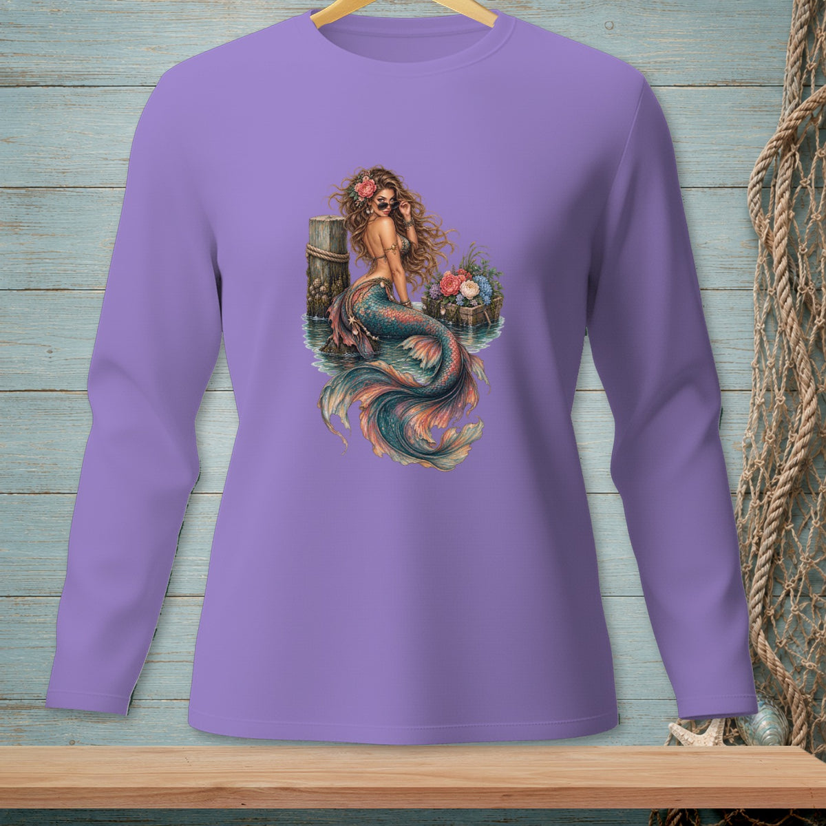Mermaid sitting on a pier with flowers and sunglasses, on a purple long-sleeve shirt.