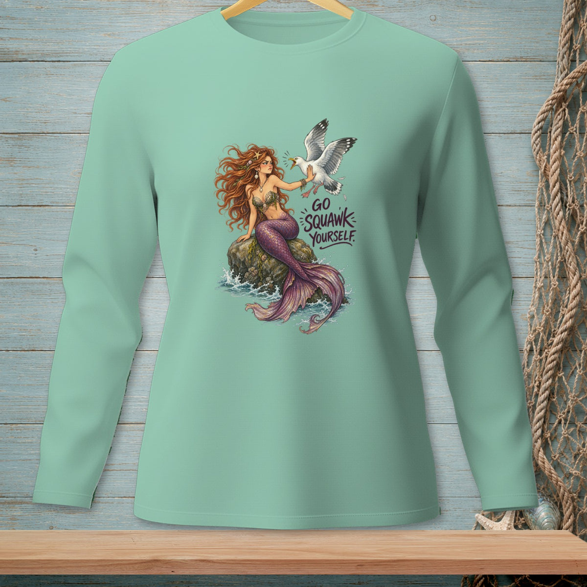 Mermaid with purple tail and seagull with "Go Squawk Yourself" text on a teal shirt.