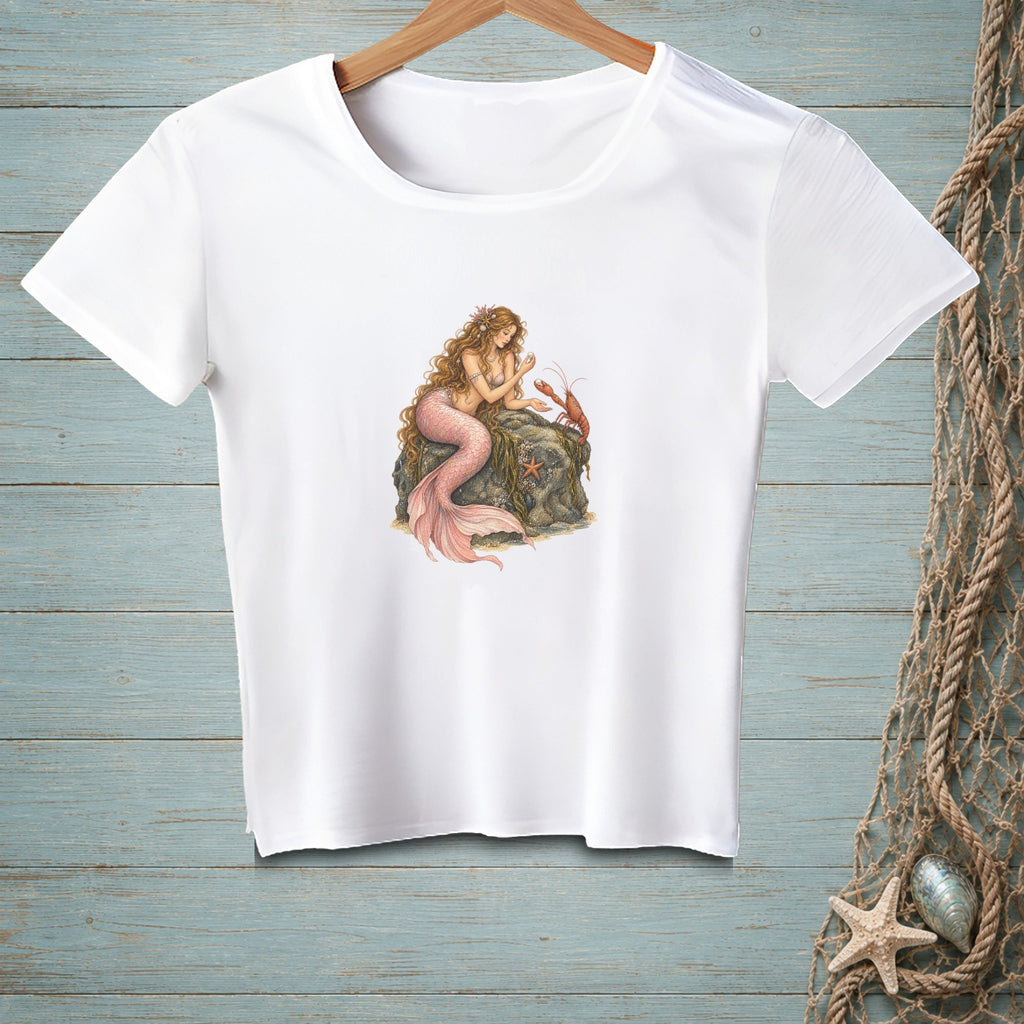 White t-shirt with mermaid and lobster illustration on a rock.