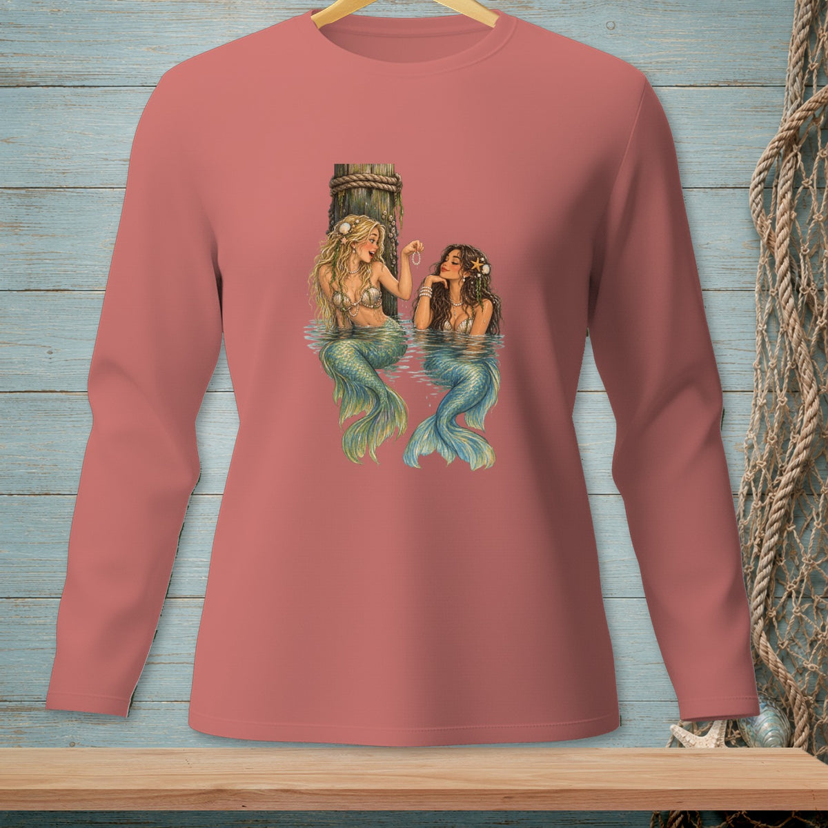 Two mermaids sitting in water next to a wooden post with ropes.