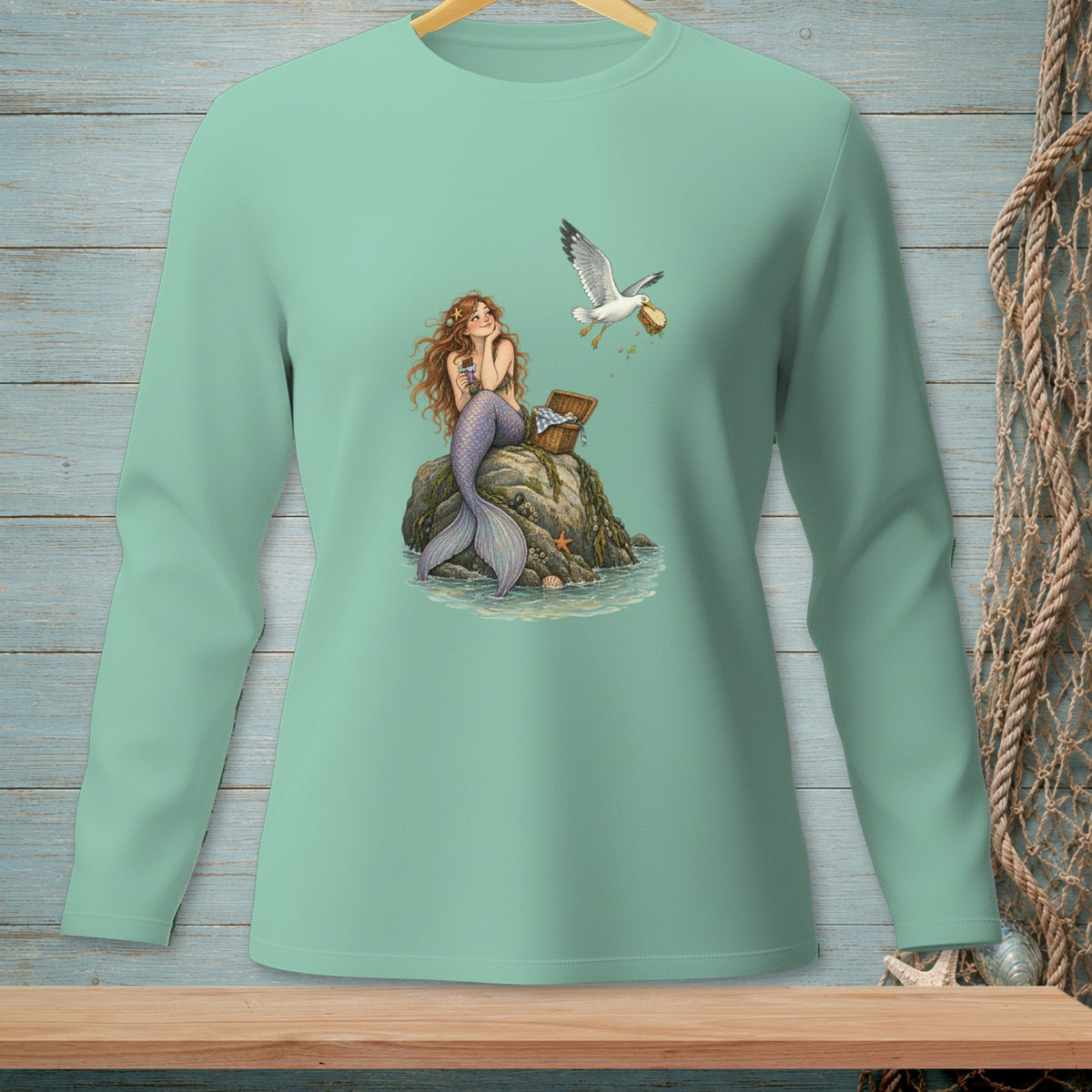Mermaid sitting on a rock with a picnic basket while a seagull steals food.