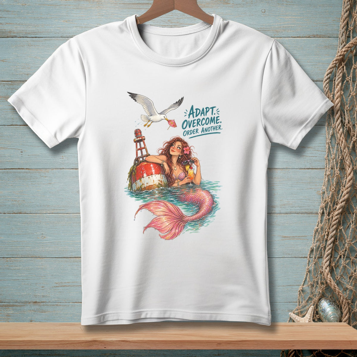 White t-shirt with illustration of mermaid and seagull with text: ADAPT. OVERCOME. ORDER ANOTHER.