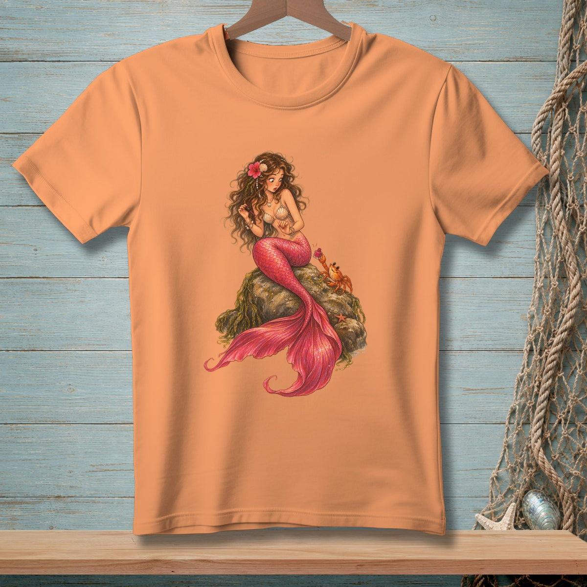 Coral t-shirt with illustration of a mermaid sitting on a rock with a crab.