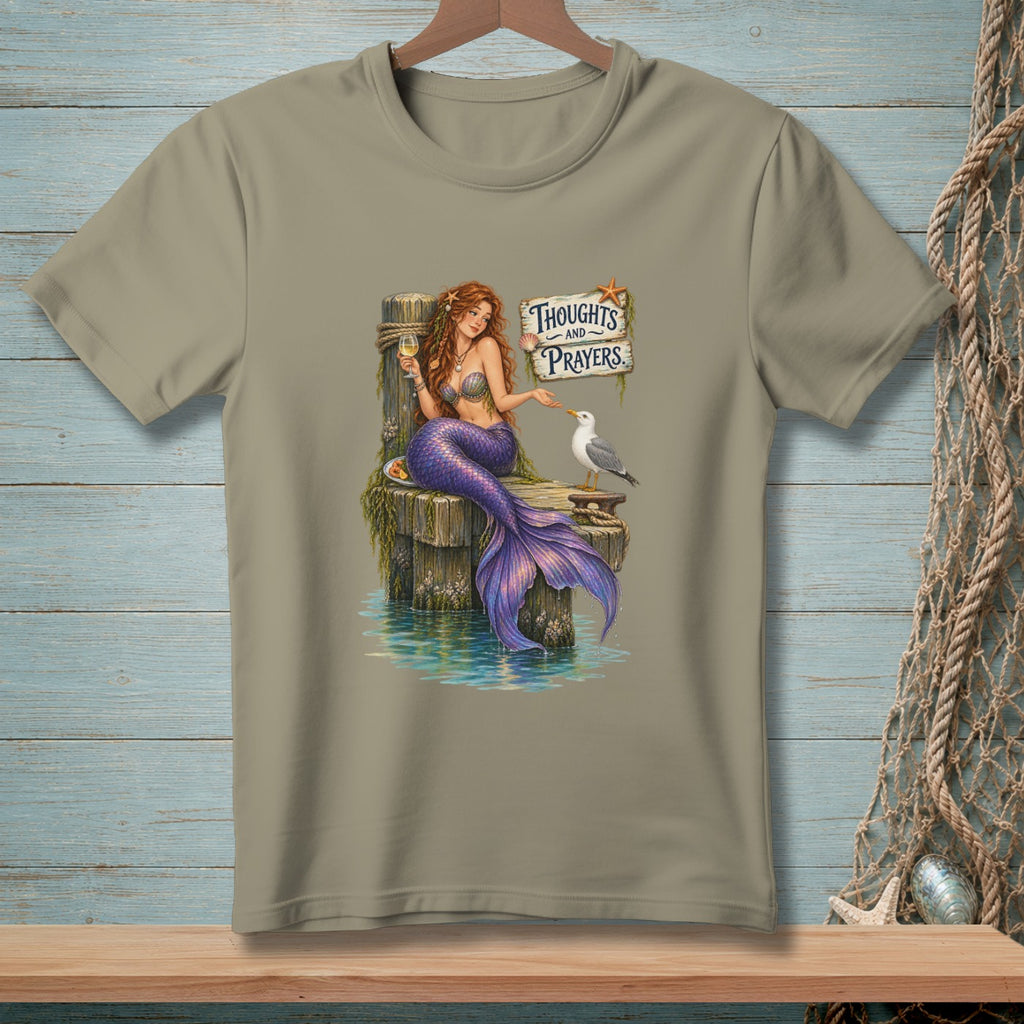 Mermaid holding wine sits on dock with seagull and sign saying "Thoughts and Prayers."