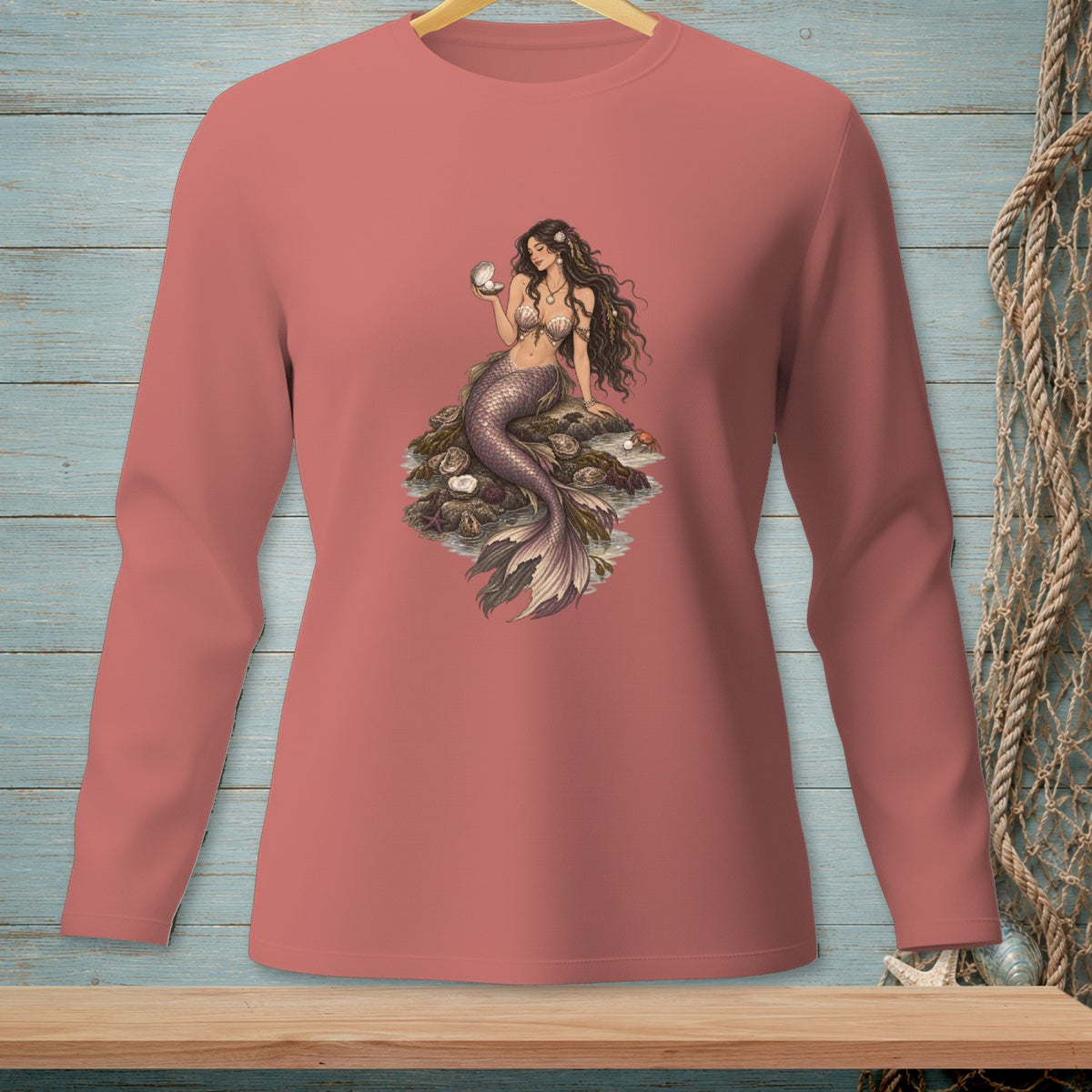 Pink long-sleeve shirt with a mermaid holding a pearl and sitting on rocks.