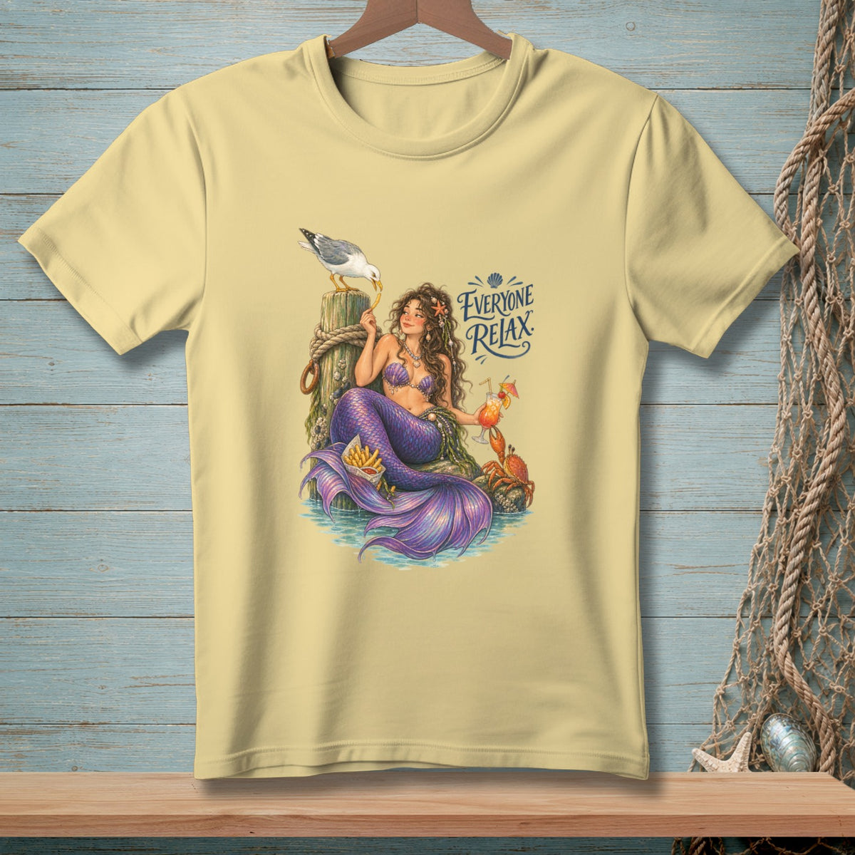 Light yellow t-shirt with a mermaid, seagull, crab, french fries, and cocktail with text "Everyone Relax".
