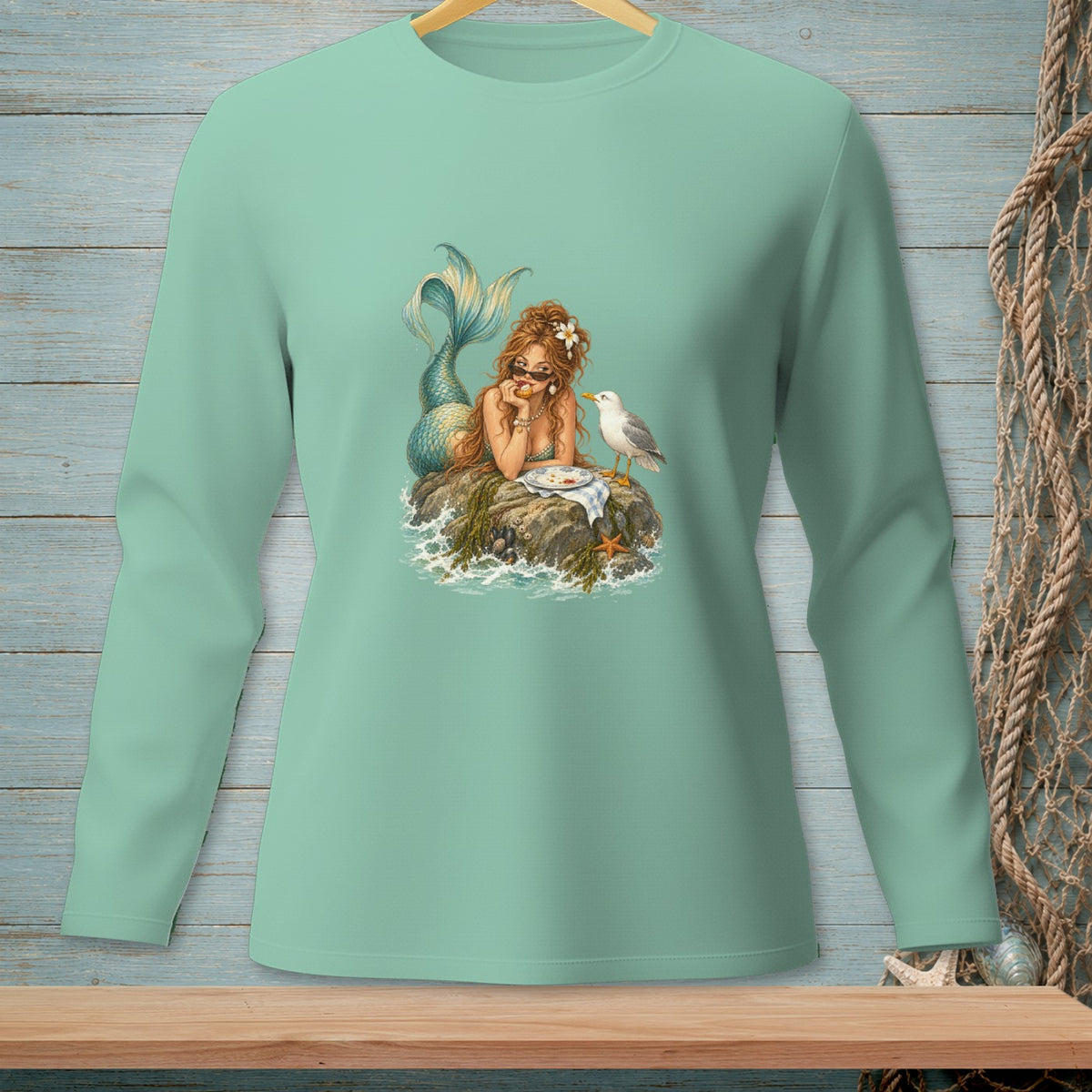 Long sleeve t-shirt with a graphic of a mermaid lounging on a rock with a seagull.