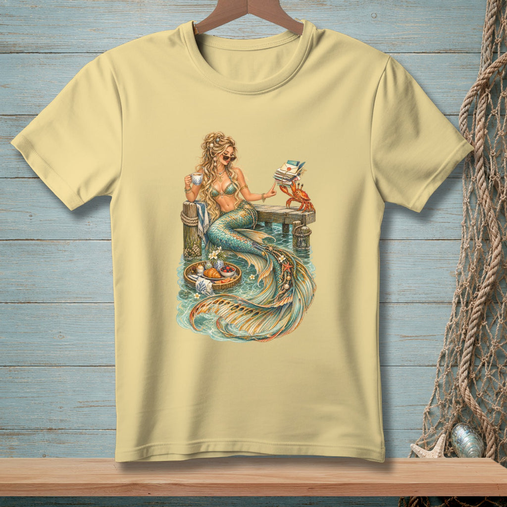 Mermaid holding coffee cup, reading mail with a crab on a pier.