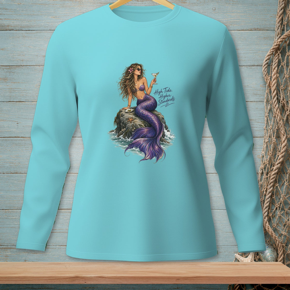 Turquoise long-sleeve shirt with a mermaid holding a cocktail on a rock.
