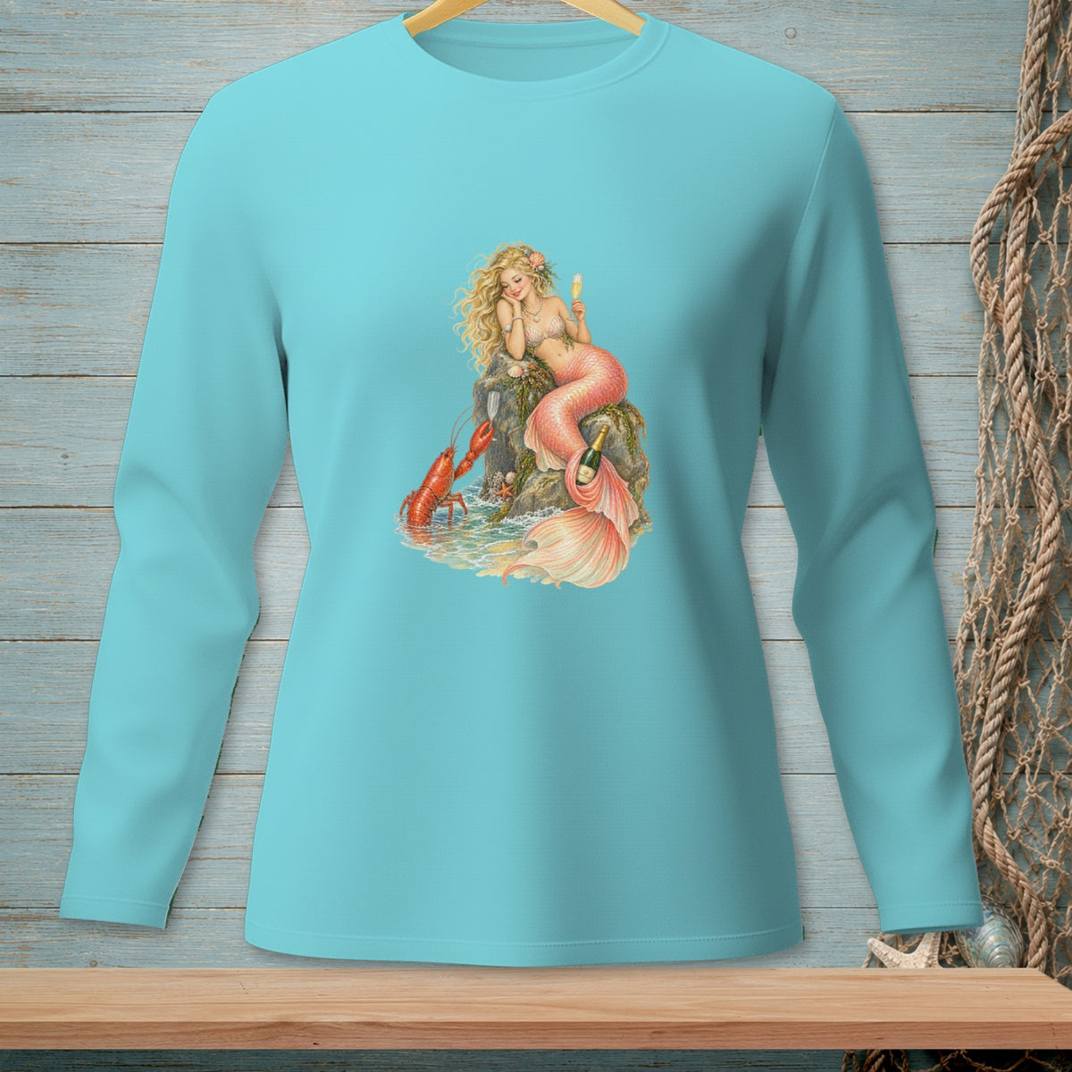 Mermaid with lobster and champagne on a rock, printed on a teal long-sleeve shirt.