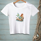 White t-shirt with a mermaid, seagull, and starfish illustration on a rock.