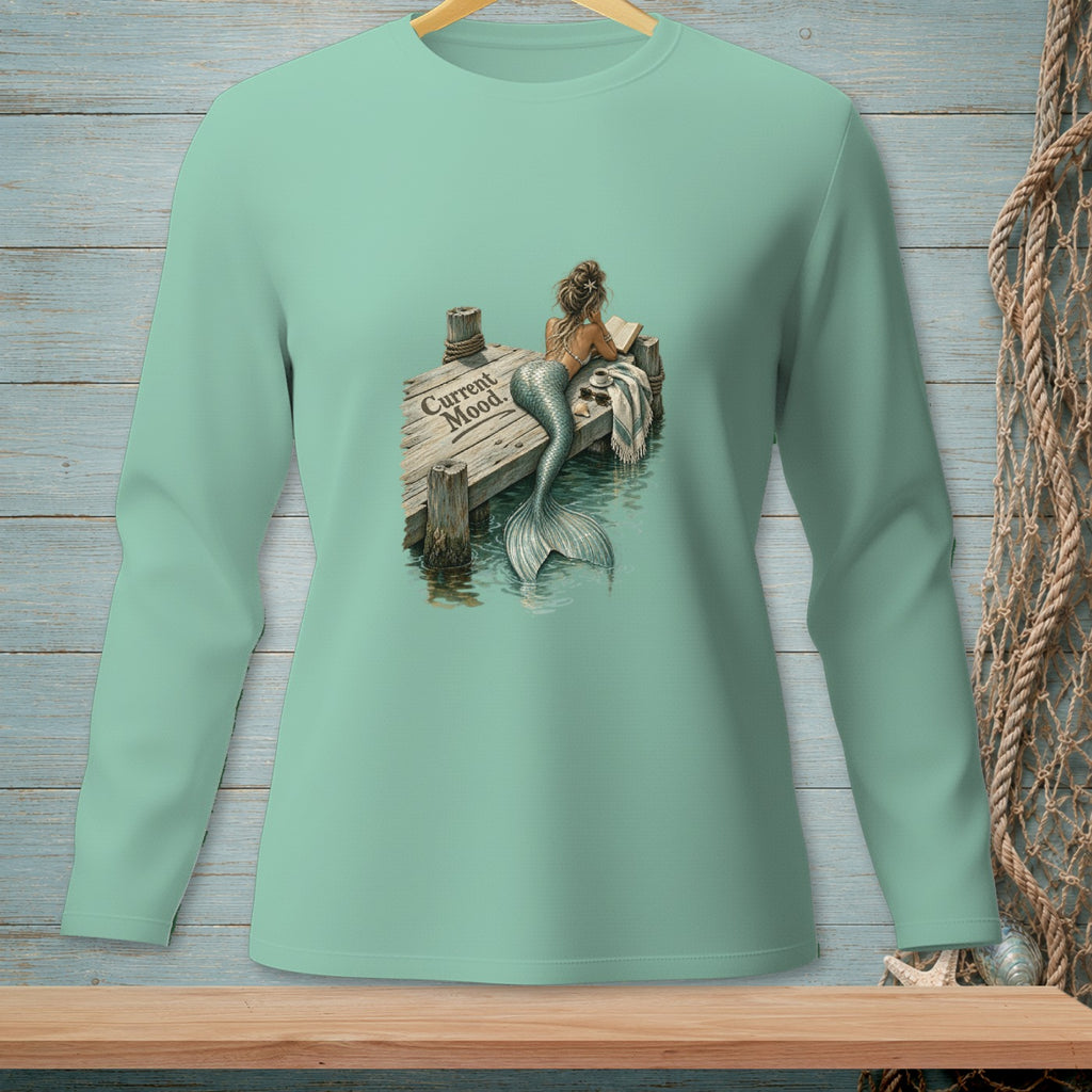 Mint green long-sleeve shirt with a mermaid reading on a dock, text "Current Mood."