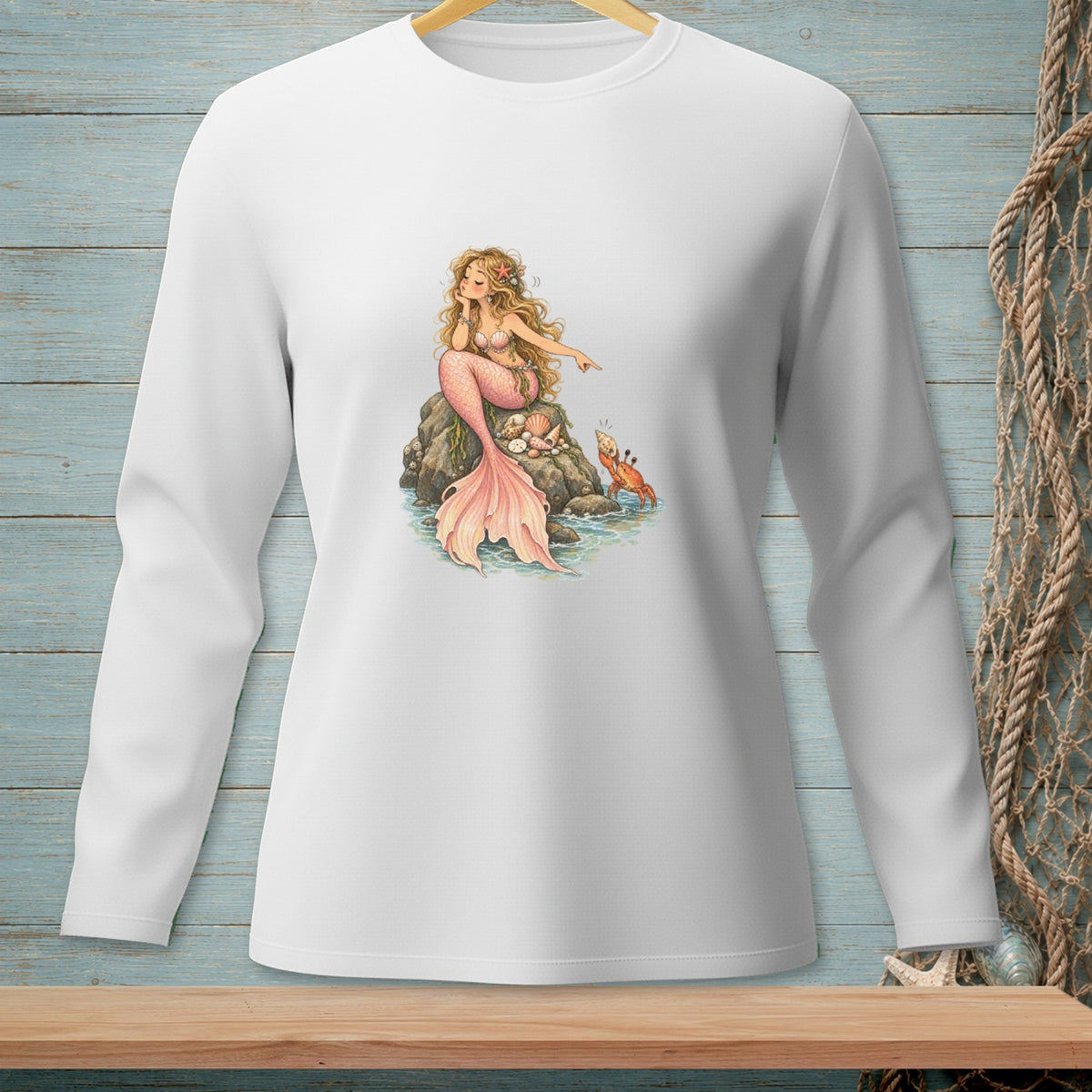 White long-sleeve shirt featuring a drawing of a mermaid sitting on a rock with a crab.