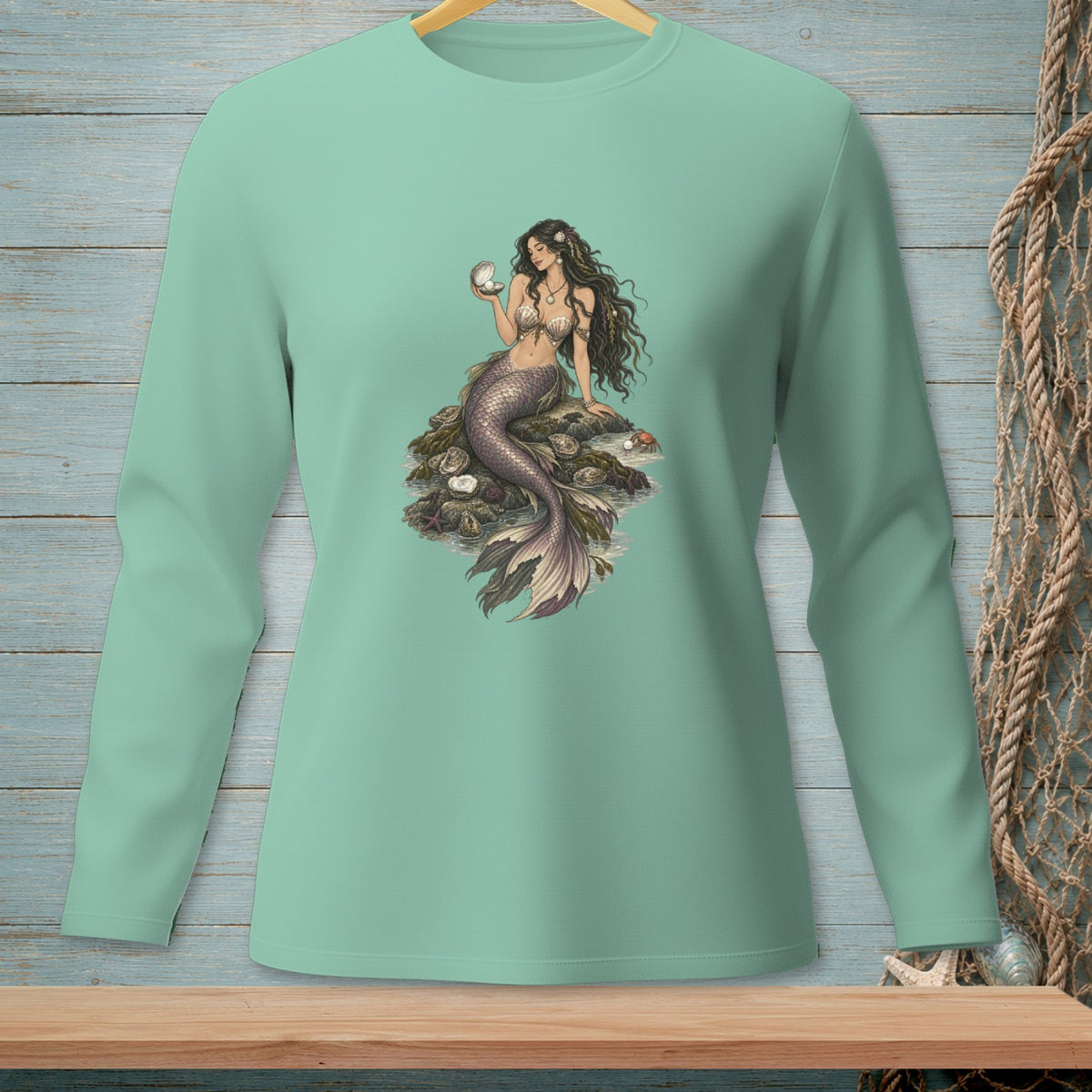 Mermaid sitting on rocks holding an open seashell with a pearl.