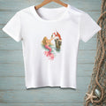 White t-shirt with graphic of a mermaid and lobster toasting with champagne.