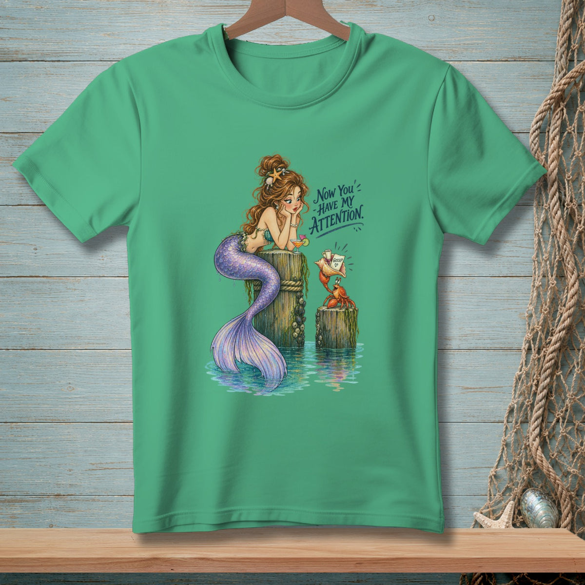 Mermaid sitting on a post with a crab and text that says "Now You've Have My Attention."