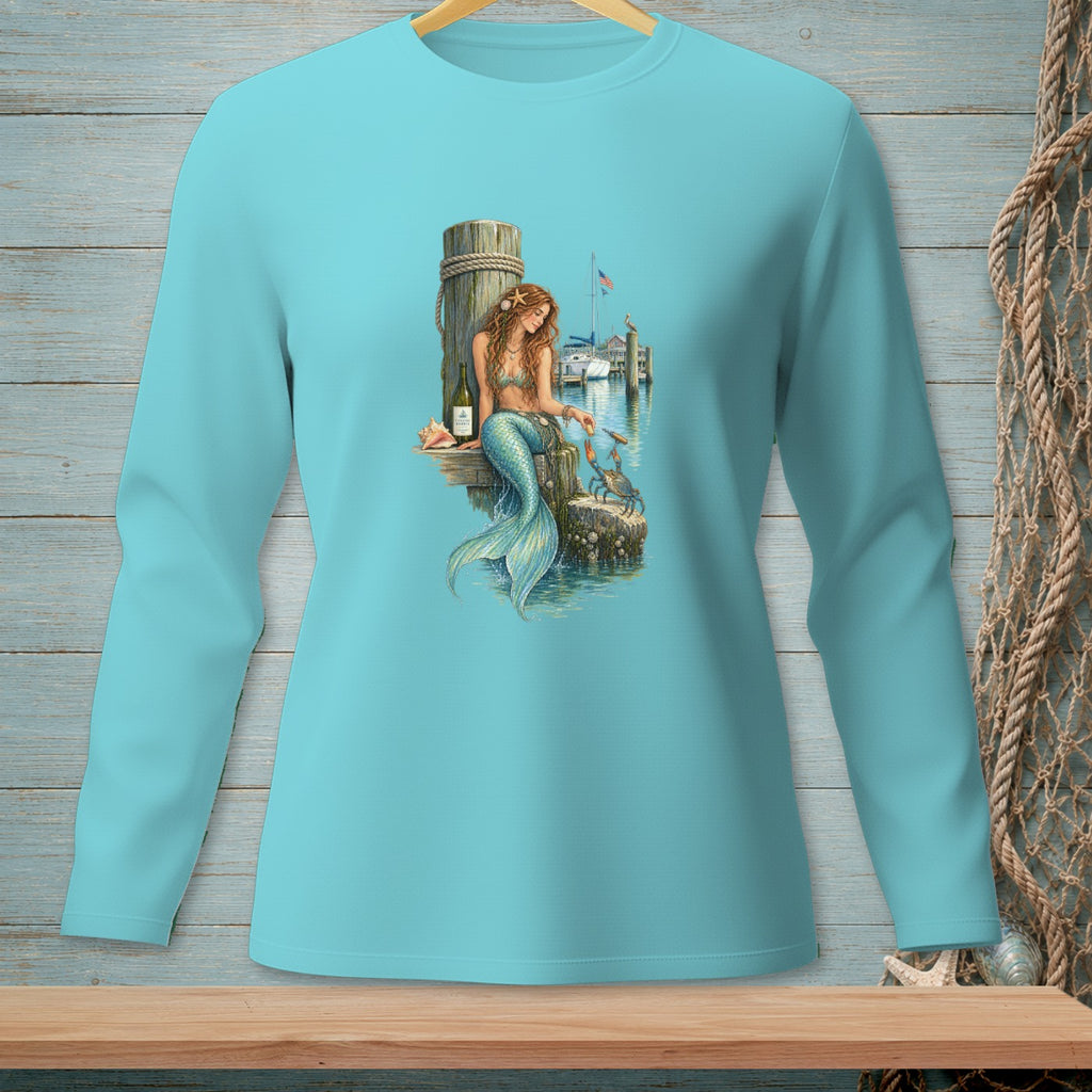 Mermaid sitting on a dock, feeding a crab, with boats in the background.