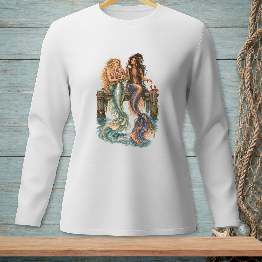 Two mermaids with colorful tails sit on a dock, one holding flowers.