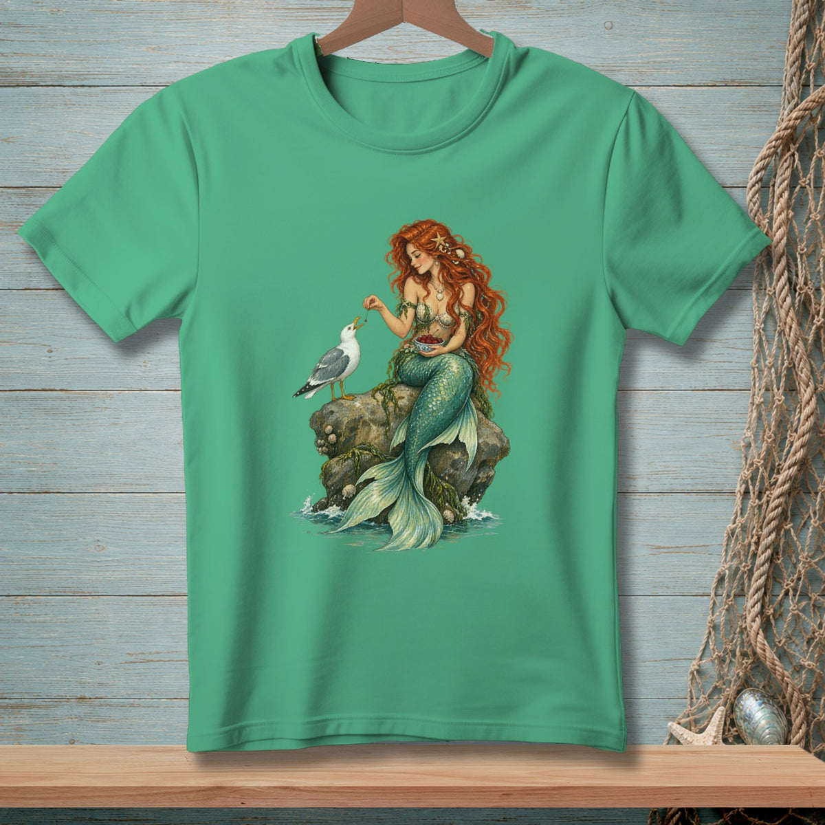 Mermaid feeding a seagull from a bowl of cherries on a rock.