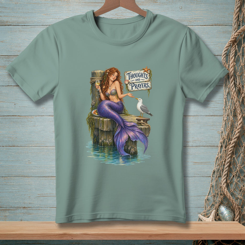 Mermaid with a glass of wine and a seagull on a pier with "Thoughts and Prayers" sign.