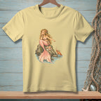 Yellow t-shirt with a drawing of a mermaid pointing at a crab on a rock.
