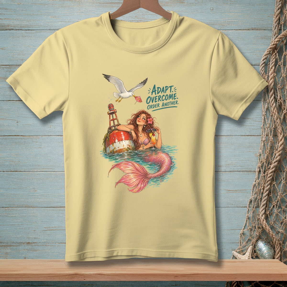 Light yellow t-shirt with mermaid, buoy, and seagull graphic and text.