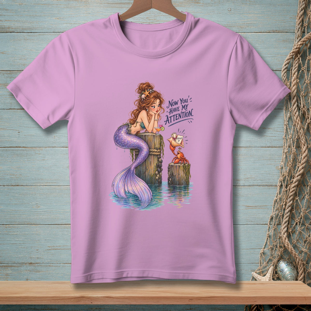 Lavender t-shirt with a mermaid, crab, and text reading "Now You've Have My Attention."