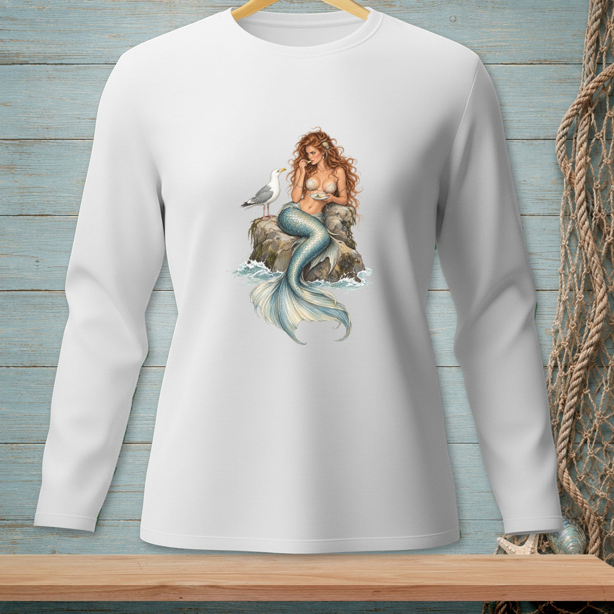 Long sleeve white shirt featuring a mermaid and seagull illustration on a rock.