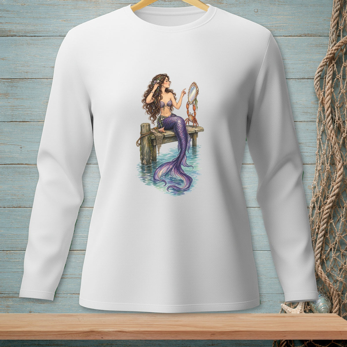 Long-sleeve white t-shirt with mermaid artwork holding a mirror on a wooden pier.