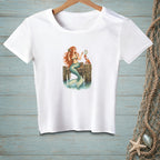 White t-shirt with a mermaid, crab, and mirror illustration on a wooden dock.