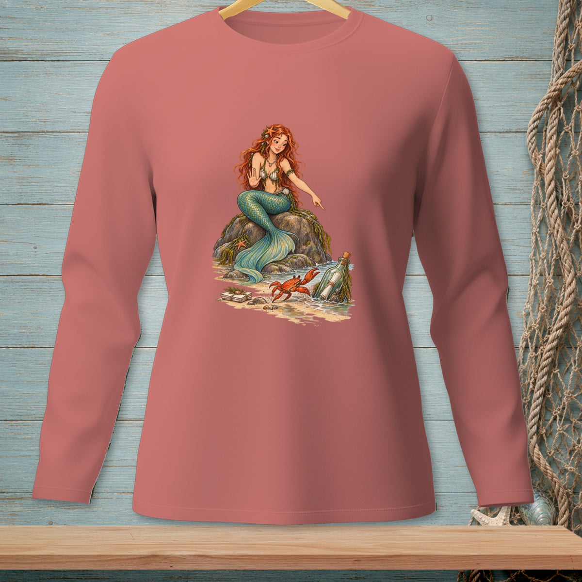 Mermaid sitting on rocks pointing at a message in a bottle with a crab nearby.