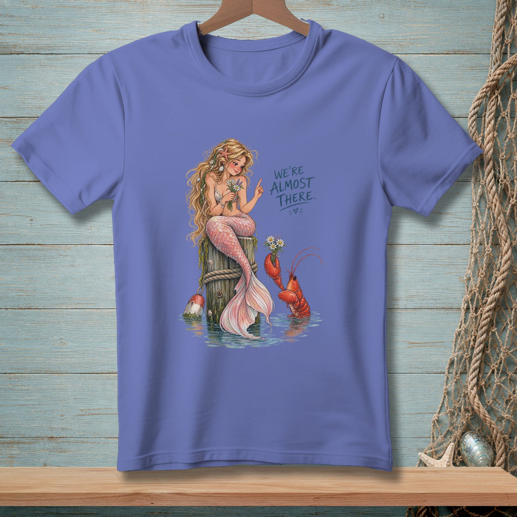Mermaid sitting on a post with lobster, text "We're Almost There."