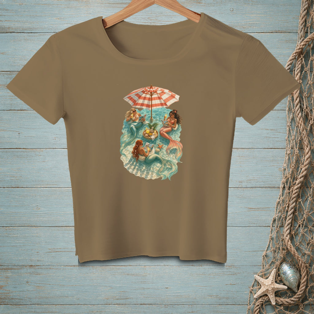 T-shirt with a graphic of mermaids relaxing under a beach umbrella on a giant seashell.