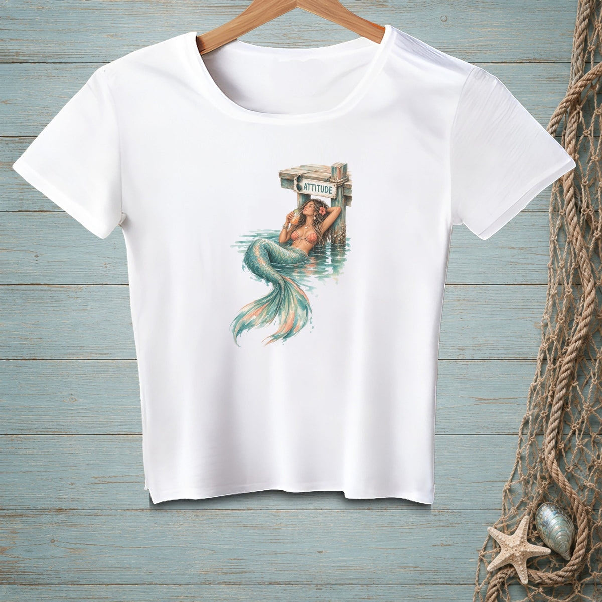 White t-shirt with a mermaid lounging by a wooden pier with the word "ATTITUDE".