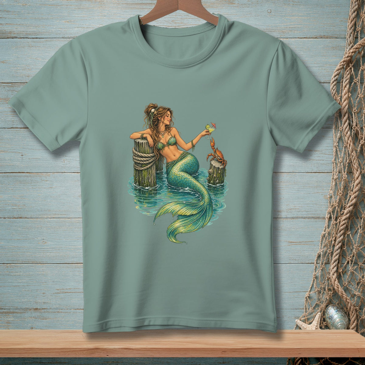 Mermaid with green tail and bikini on wooden posts, holding a drink, a crab nearby.